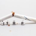 broken cigarette with the word stop on gray background close. stop smoking concept
